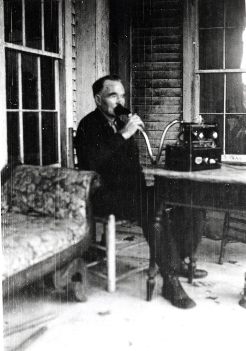 A man from the 19th century sitting outside creating a wax cylinder recording.